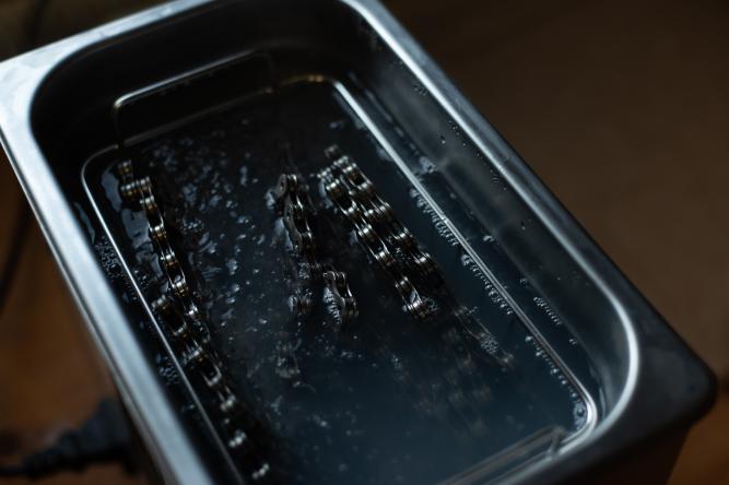 PROFI: KETTENREINIGUNG PER ULTRASCHALL
Nach zwei Durchgängen mit Waschbenzin im Einmachglas geht die Kette - anstelle des Acetons - in ein Ultraschallreinigungsgerät. Durch die Ultraschallbehandlung, eine möglichst hohe Temperatur von zirka 80 Grad und ein leicht alkalisches Reinigungsmittel wird noch das letzte bisschen Fett entfernt.
Vorteile: Maximal effizient
Nachteile: Anschaffung eines Ultraschallgeräts, zusätzlicher Zeitaufwand, Kosten/Aufwand/Energiebedarf für eine einzelne Kette ist eher fragwürdig
Resultat: Vollständig gereinigte und entfettete Kette.
