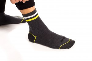 Die Merino Socken mit längerem, dicken Schaft tragen einen weißen Streifen und einen in Signalfarbe.